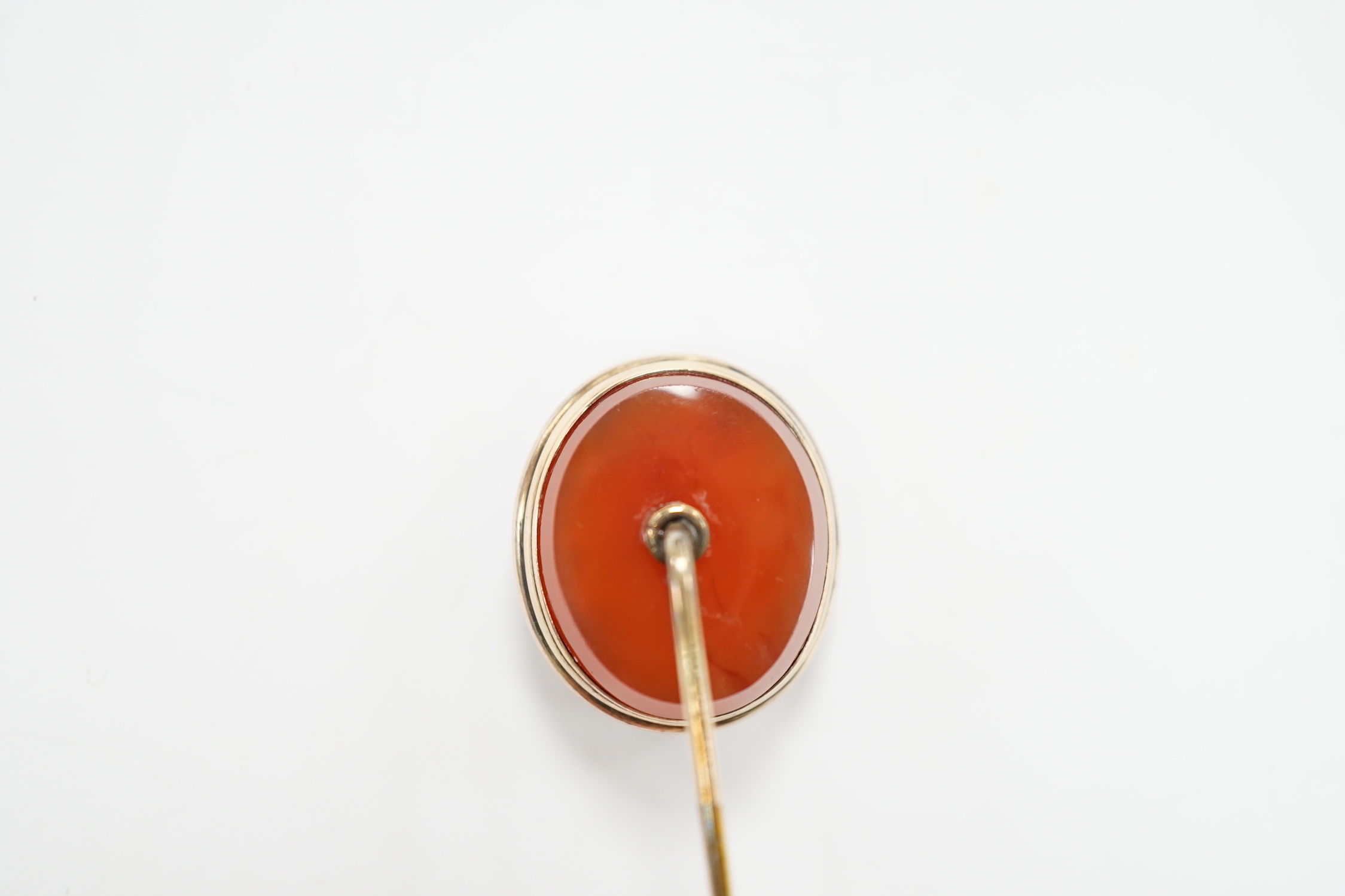 An early 20th century yellow metal and oval intaglio chalcedony set stick pin, 77mm.